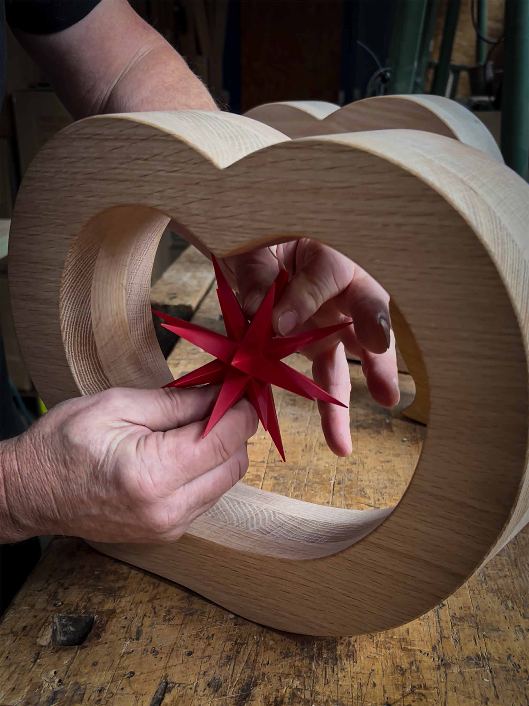 Ein Herrnhuter Stern wird in ein handgefertigtes Holzherz eingesetzt